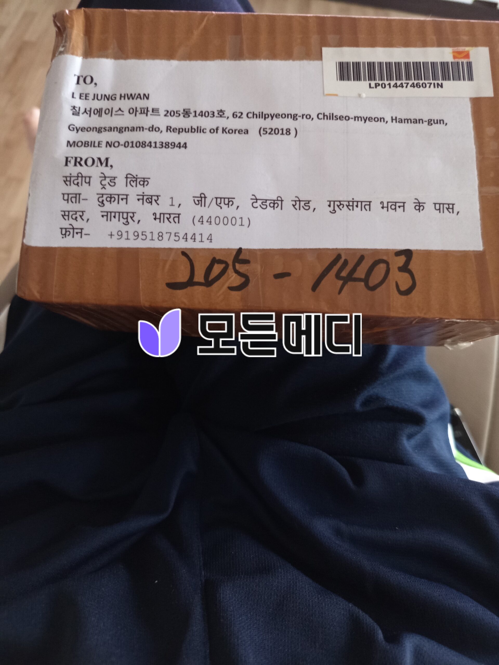 Cardboard parcel with a printed address label, barcode, and handwritten code 105-1403.